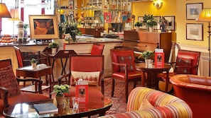 Un coin lecture accueillant, avec des fauteuils en cuir, une table en verre et des étagères remplies de livres et d’objets décoratifs.