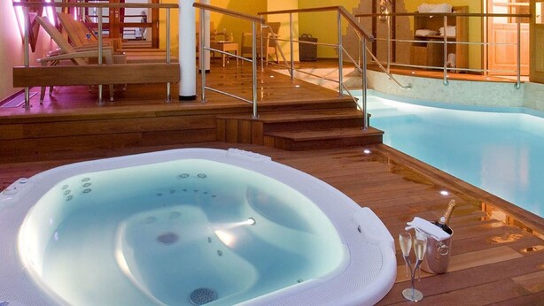 Un bain à remous avec une terrasse en bois, un escalier et une piscine.