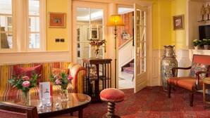 Une pièce comprenant un canapé, une table avec un vase de fleurs, une lampe et une chaise avec un coussin à motifs.