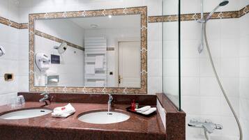 Un baño de hotel con dos lavamanos, un espejo grande y una ducha.
