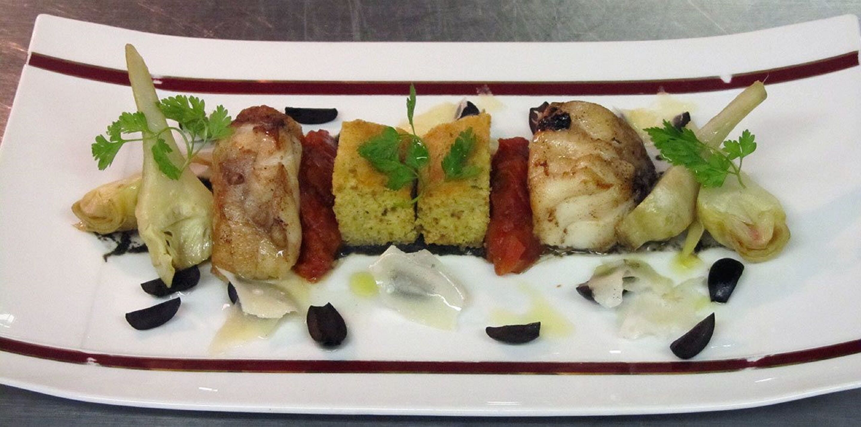 Une assiette garnie de différents aliments, notamment un morceau de viande, des légumes et une petite portion de pain, le tout décoré d’herbes aromatiques.