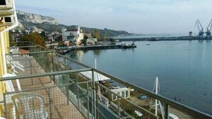 A waterfront view with a balcony, a distant bridge, and industrial cranes. - Lotos Hotel (Balchik)
