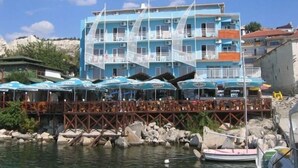 A coastal building with multiple balconies, a wooden pier, and several umbrellas. - Lotos Hotel (Balchik)