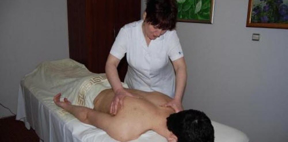 A massage therapy session in a room with a bed and a wooden door.