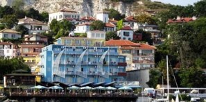 A coastal building with multiple balconies, a waterfront terrace, and a hillside backdrop. - Lotos Hotel (Balchik)