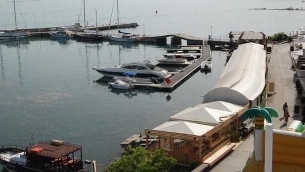A marina with boats docked, a covered structure, and a building with a sloped roof. - Lotos Hotel (Balchik)