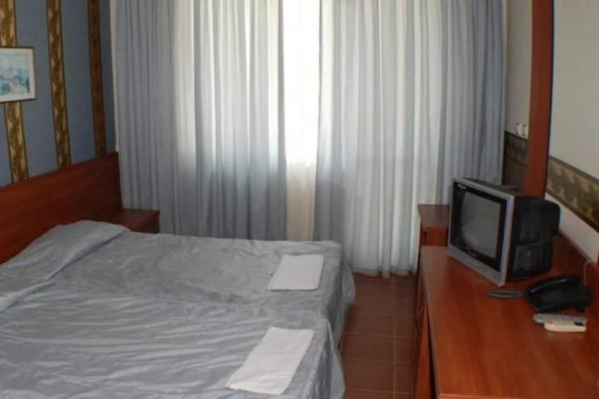 A hotel room with a bed, a television, and a desk with a telephone.