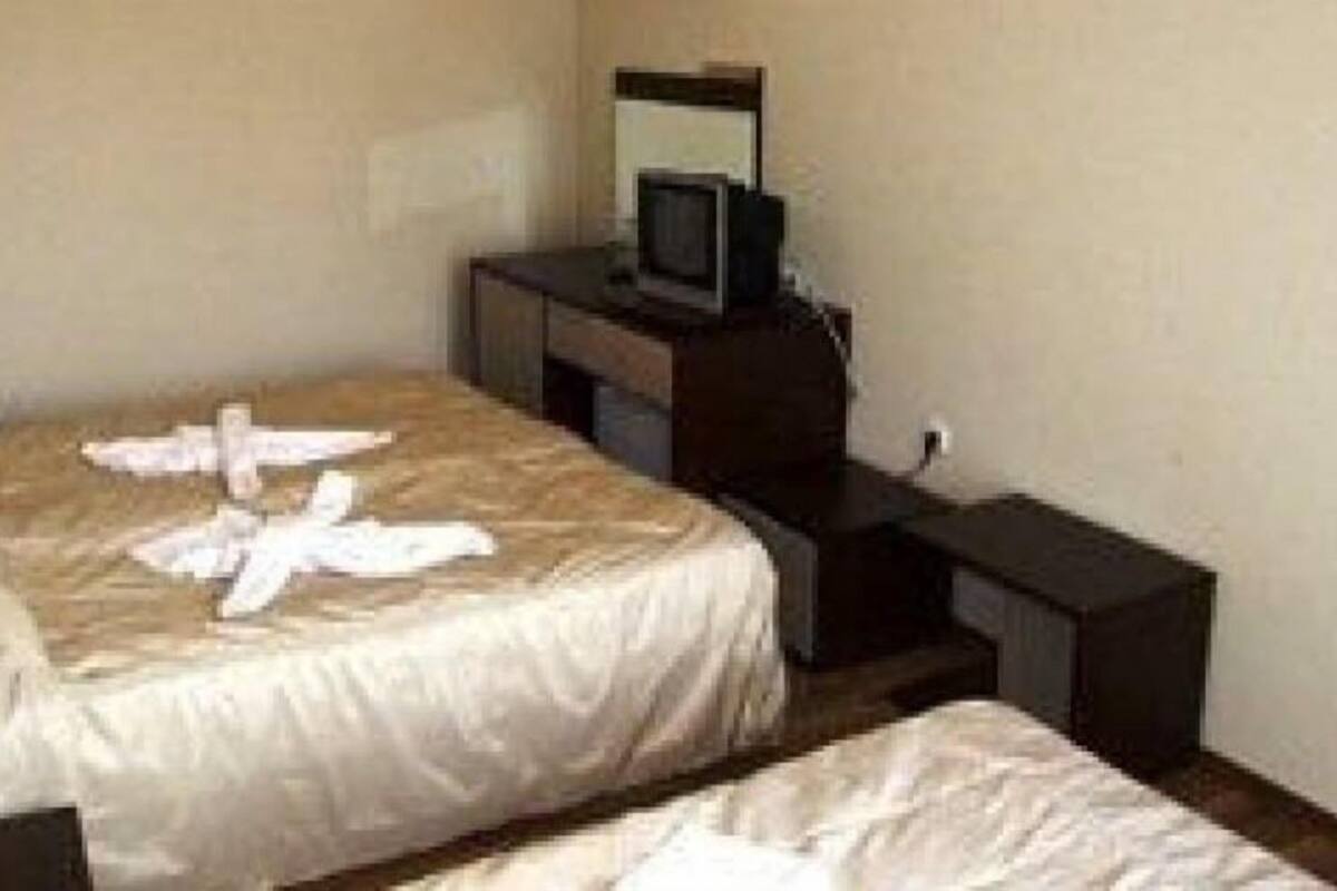 A hotel room with a bed, a television on a stand, and a small desk with a chair.
