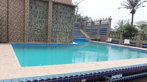 Una piscina con un muro de piedra y escalones con baldosas que conducen a un portón.