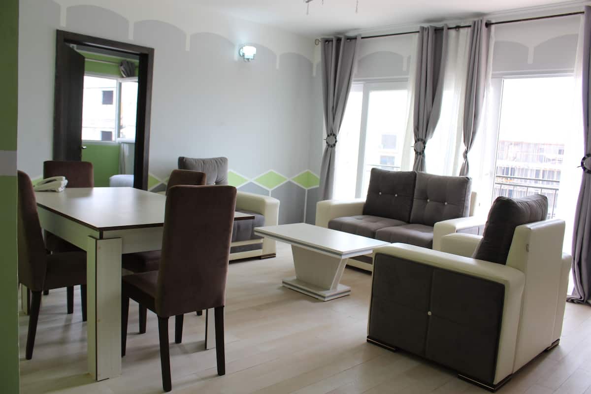 Uma sala de estar moderna com uma mesa de jantar, cadeiras, um sofá e uma mesa de centro.