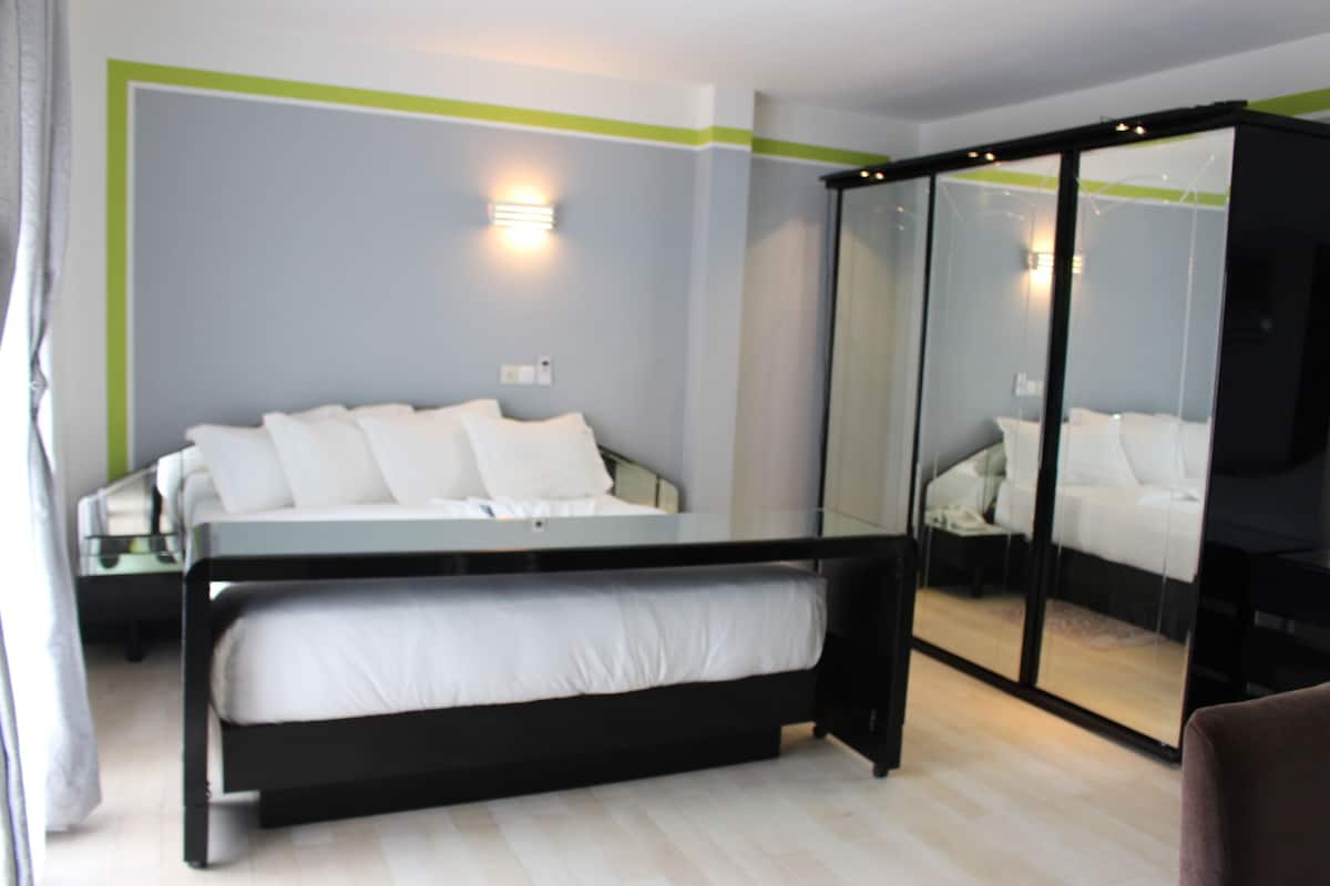 Quarto moderno com cama, mesa de cabeceira e armário com espelho.