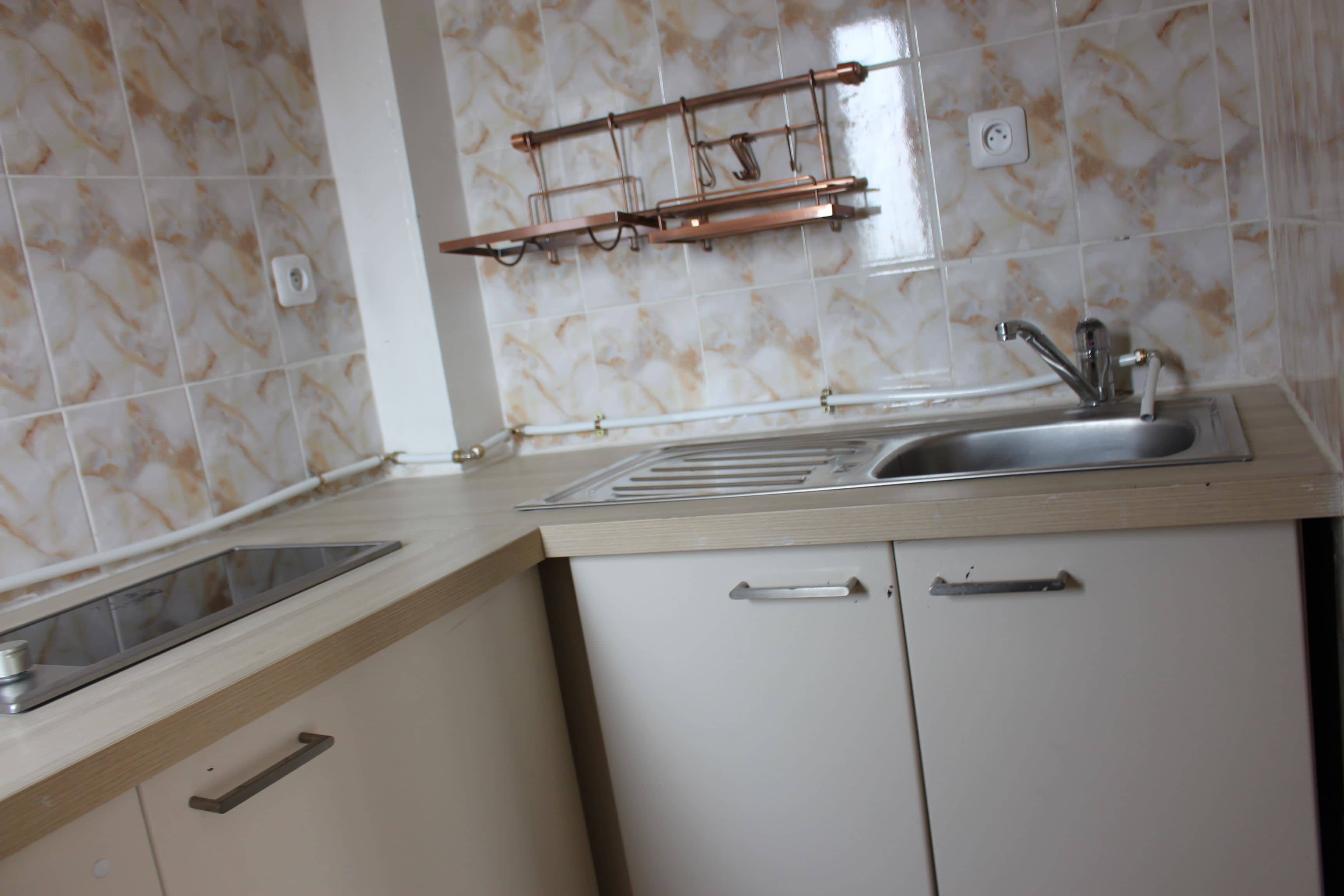 A kitchen with a sink, countertop, and cabinets.