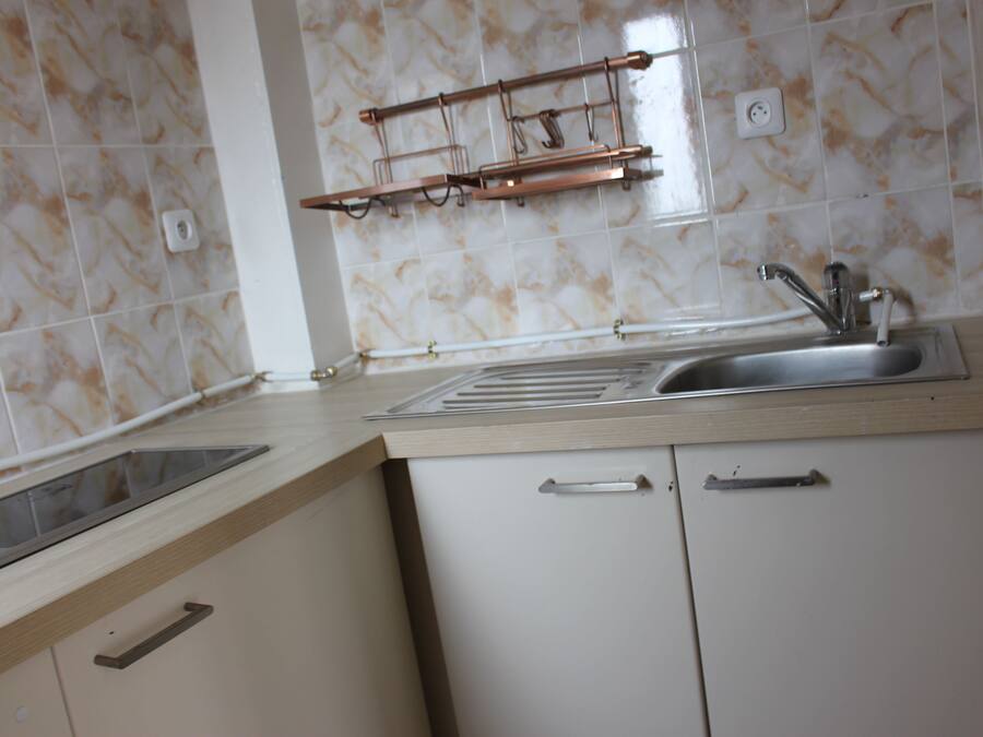 A kitchen with a sink, countertop, and cabinets.