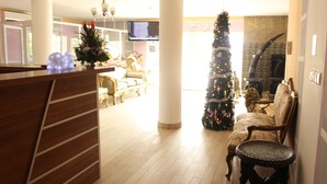 Un amplio espacio de sala con un mostrador de recepción de madera, un gran árbol de Navidad y una chimenea.