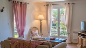 Une pièce confortable avec un lit, une chaise, une table et un téléviseur.