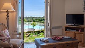 Une chambre avec vue sur une piscine, une télévision et une table avec des livres et une boîte.