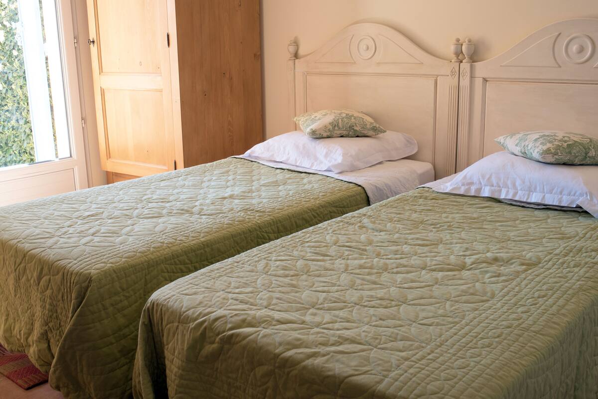 Two single beds with green quilts, white pillows, and a wooden headboard.
