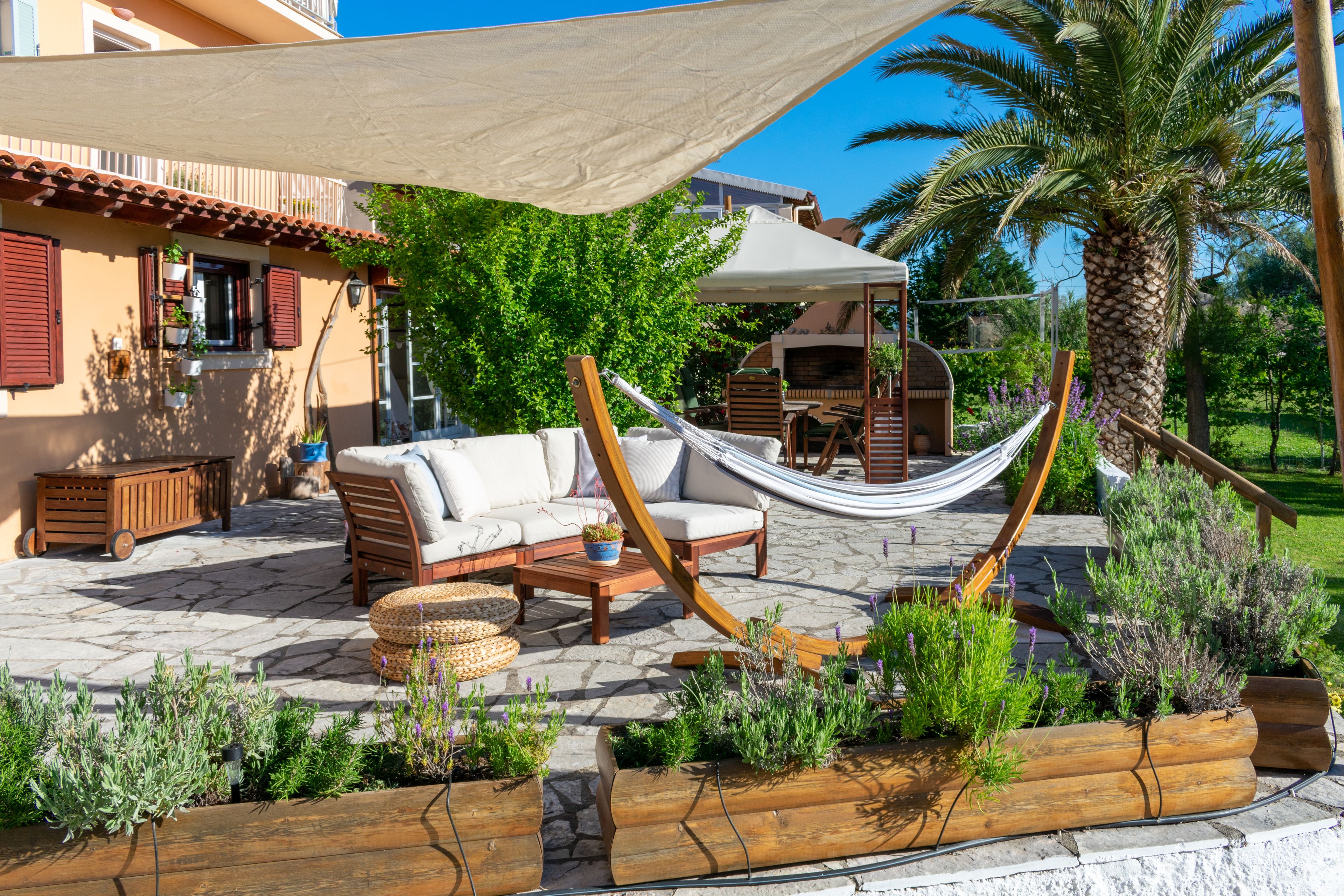 An outdoor patio with a hammock, wicker furniture, and potted plants.