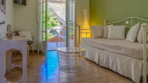 Une pièce comprenant un lit, une table ronde et une chaise. Une porte donne sur un espace extérieur offrant une vue sur la verdure.