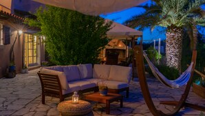Une terrasse extérieure avec un canapé, un hamac et une table sur laquelle est posée une lanterne.