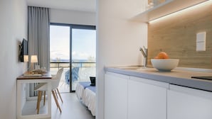 Une chambre d’hôtel moderne dotée d’un balcon, d’un coin repas et d’une cuisine avec un mur d’accent en bois.