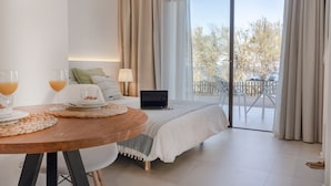 Une chambre avec un lit, un ordinateur portable, une table avec des verres de jus d’orange et une vue sur l’extérieur grâce à une porte coulissante.