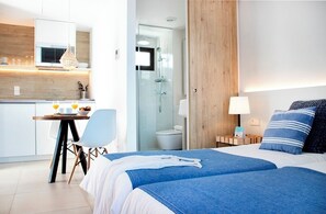 A modern hotel room with a bed, bedside table, lamp, and a shower area. - Aparthotel La Gaviota (Formentera)