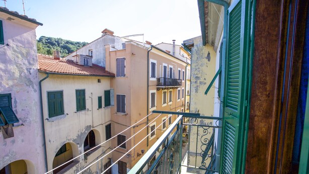 Una calle estrecha flanqueada por edificios con balcones y ventanas de arco.