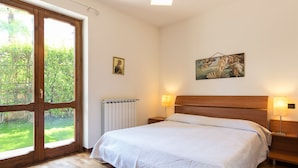 Una camera da letto con un'ampia finestra, un letto, un comodino e un quadro appeso al muro.