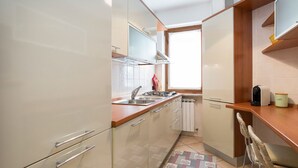 Una cucina compatta con mobili bianchi, un piano di lavoro in legno, un forno integrato e una finestra che offre luce naturale.