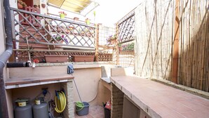 A patio area with a tiled floor, a metal railing, and potted plants. - Appartamento Bilo San Rocco (Portoferraio)