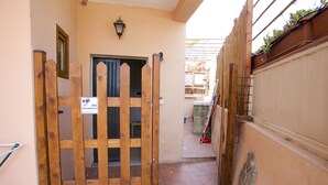 A narrow alleyway with a wooden gate, a door, and a wall with a sign. - Appartamento Bilo San Rocco (Portoferraio)