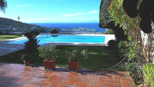 Une piscine avec vue sur la mer et sur une colline.