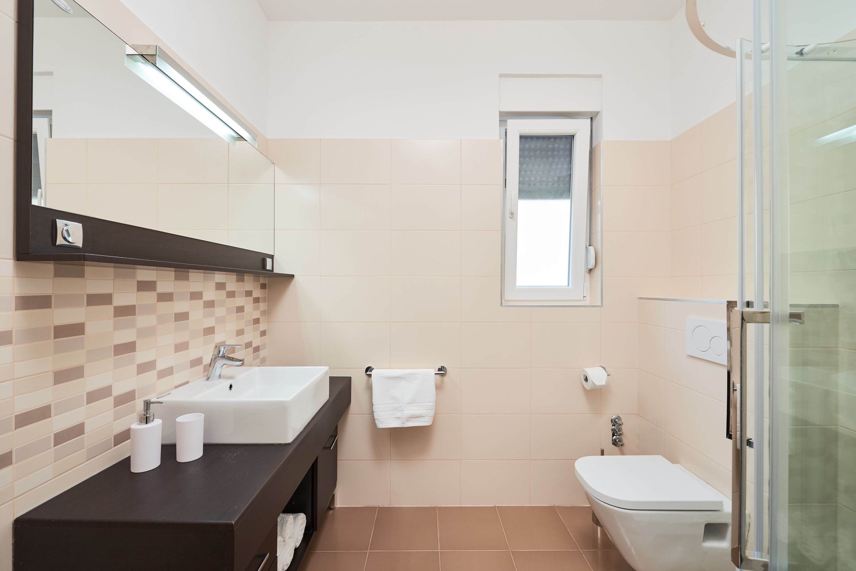 A modern bathroom with a sink, mirror, and toilet.