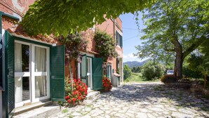 Une rue pavée menant à un bâtiment aux volets verts et à la façade en pierre.