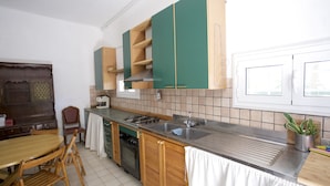 Une cuisine avec des meubles de rangement en bois, une cuisinière, un évier et un coin repas avec des chaises.