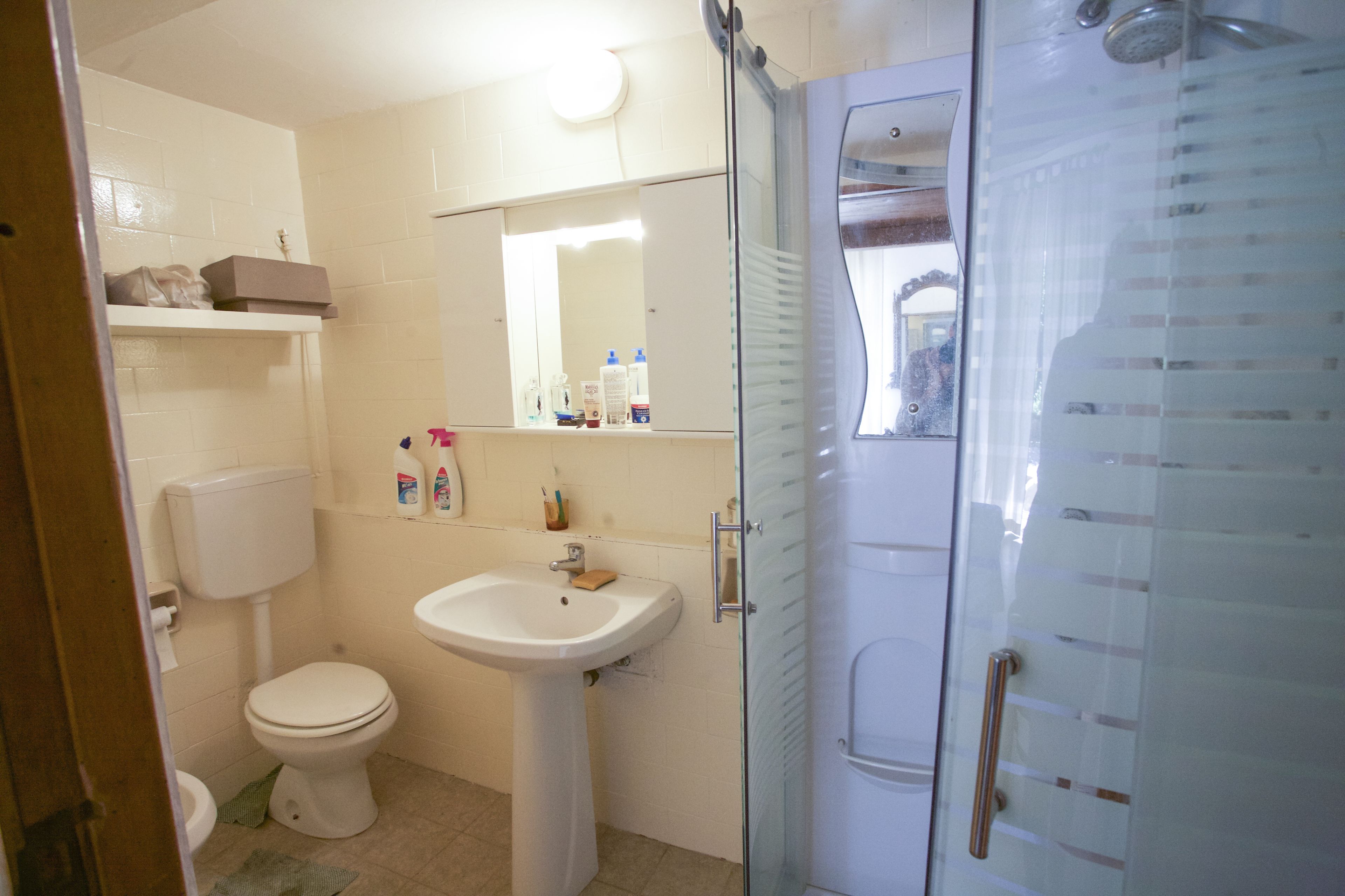 Une salle de bain équipée de toilettes, d’un lavabo et d’une douche à parois en verre.