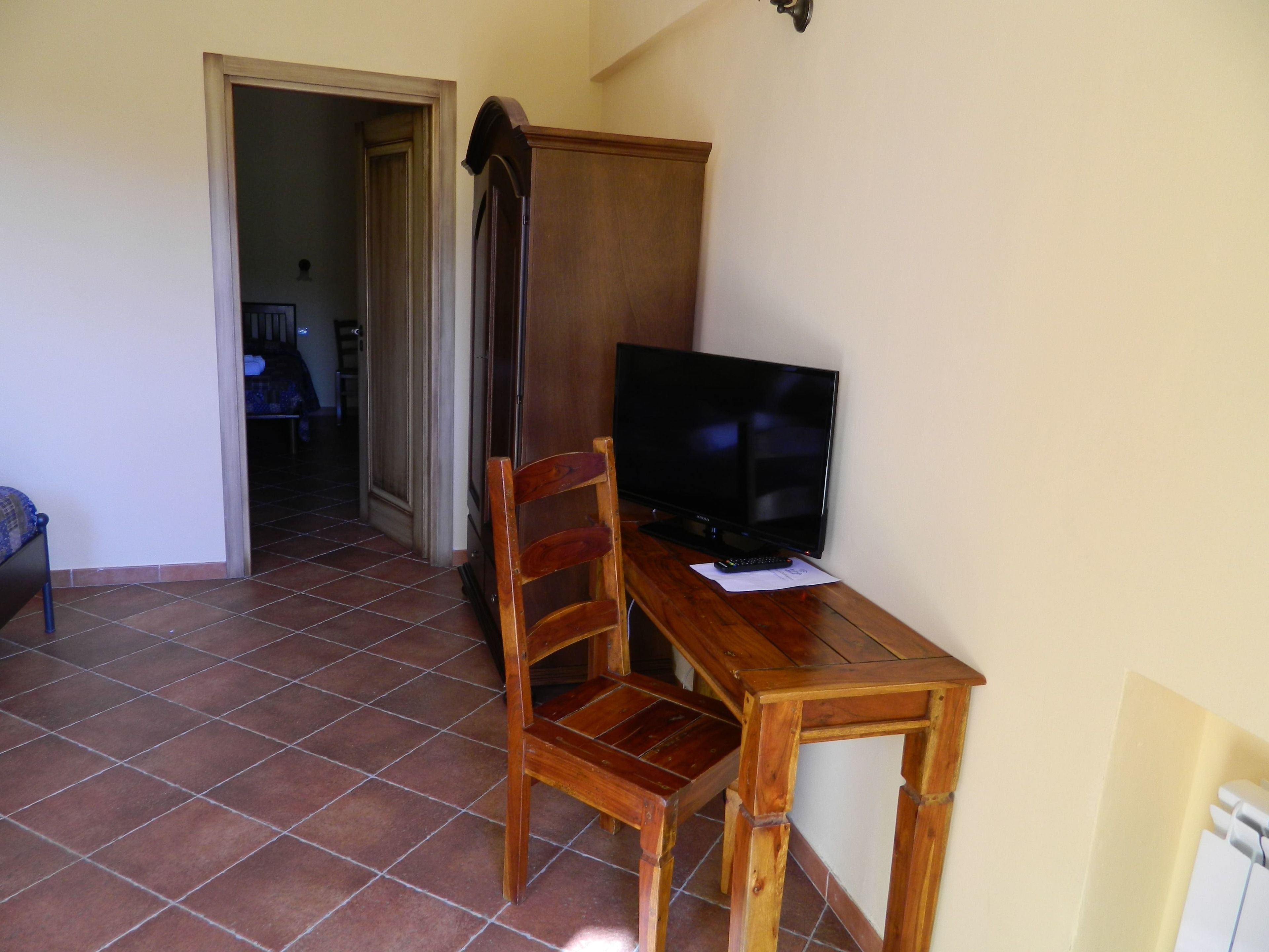 A room with a wooden table, a television, and a chair. There is a door leading to another room.