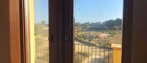 A room with large windows offering a view of a paved area and distant buildings.