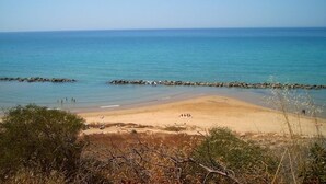 Uma praia com águas azul-claras, areal arenoso e paredões rochosos.