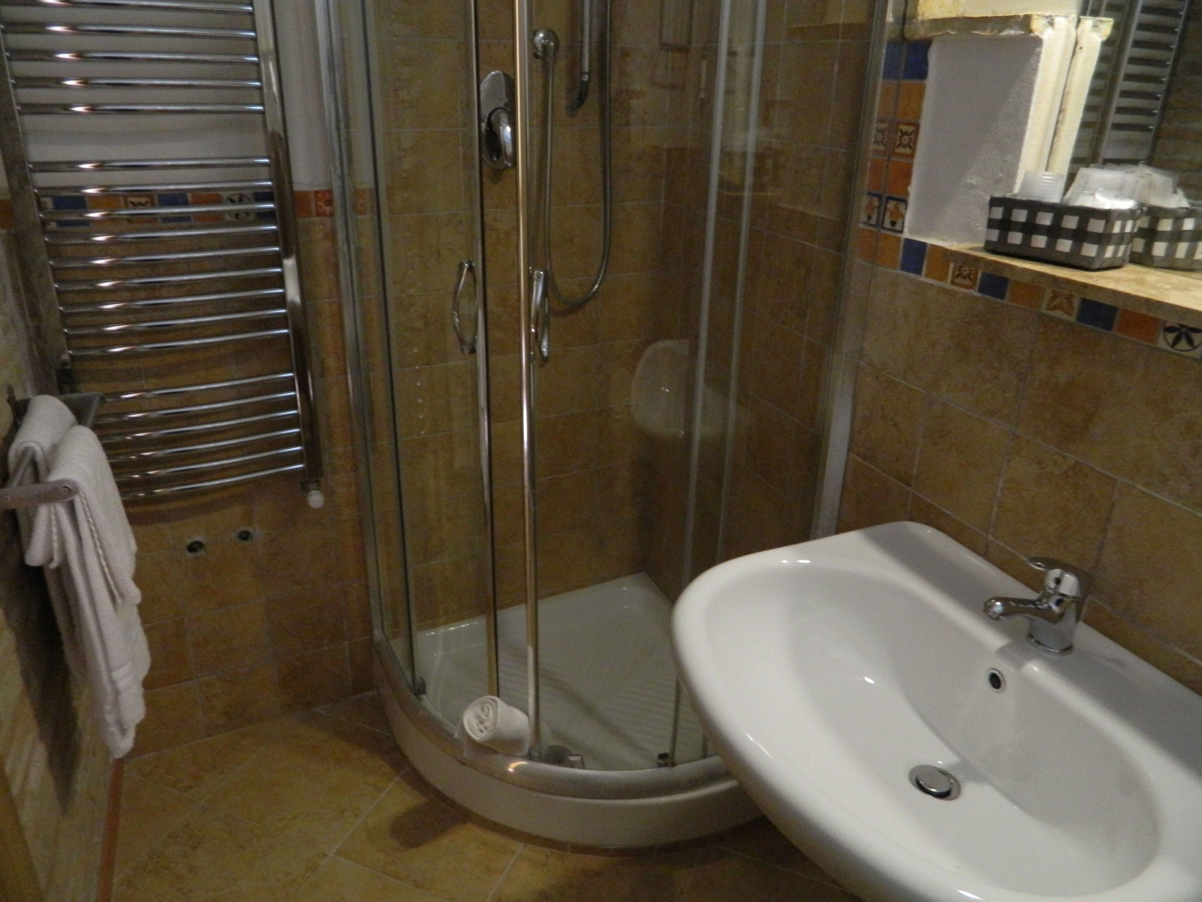 A bathroom with a glass-enclosed shower, a white sink, and a towel rack.