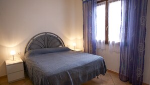 A bedroom with a bed, nightstands, and curtains. - Appartamento Bilo Sofi (Campo nell'Elba)