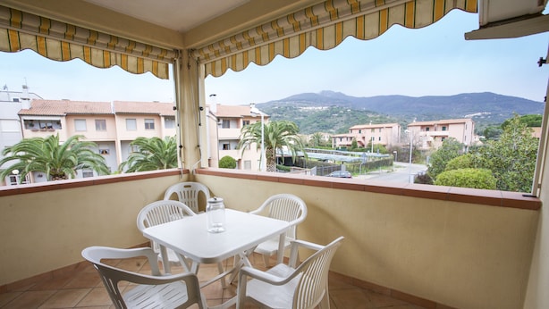 A balcony with a white table and chairs, a view of buildings and mountains in the background. - Appartamento Bilo Sofi (Campo nell'Elba)