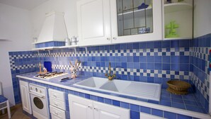 A kitchen with blue and white checkered tiles, white cabinets, and a double sink. - Appartamento Bilo Sofi (Campo nell'Elba)