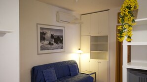 A room with a blue sofa, a framed photograph on the wall, a lamp, and a white cabinet. - Appartamento Bilo Sofi (Campo nell'Elba)