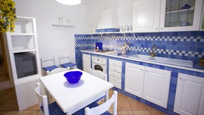 A compact kitchen with white cabinets, a blue tiled backsplash, and a white countertop. - Appartamento Bilo Sofi (Campo nell'Elba)