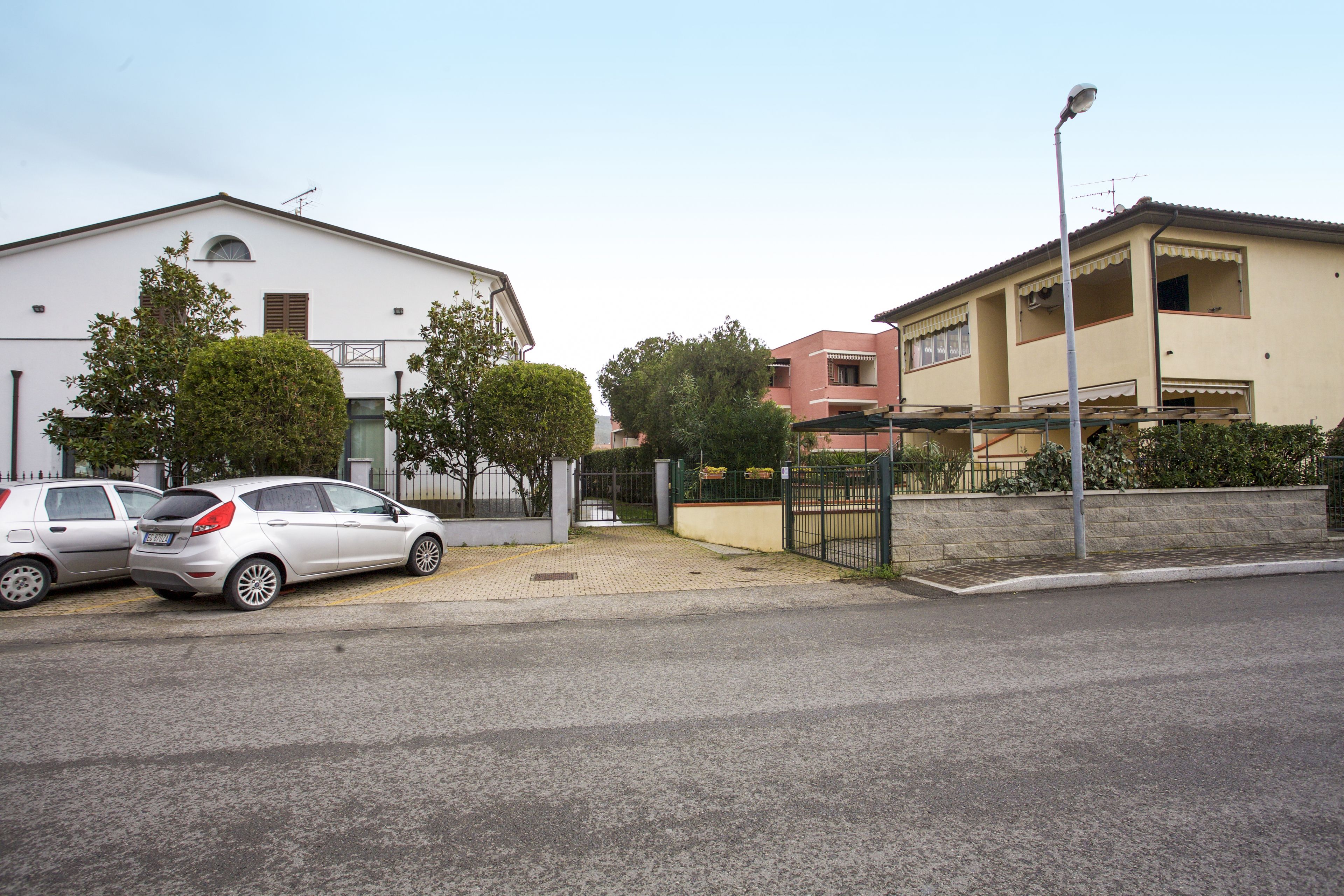 A residential street with two houses, a parked car, and a streetlight.