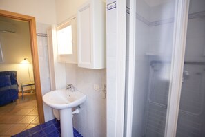 Een badkamer met een wit wastafel, een spiegel en een douchecabine.