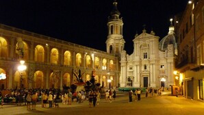 Une vaste place où se trouve un bâtiment historique remarquable, avec un dôme imposant et un clocher.