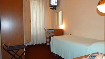 Ein Hotelzimmer mit Bett, Schreibtisch mit Stuhl, Fernseher, Spiegel und Nachttischtelefon.